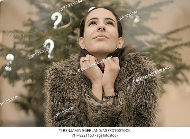 woman looking up searching for answer and inspiration, in front Christmas tree with lights of question marks, faith, hope, in Munich, Germany