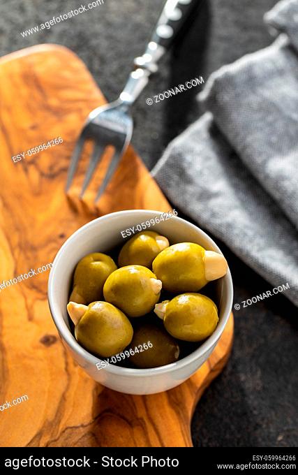 Pitted green olives stuffed with almonds in bowl on cutting board