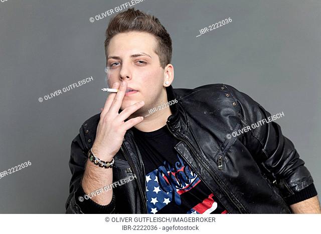 Young man wearing a leather jacket and smoking a cigarette, portrait