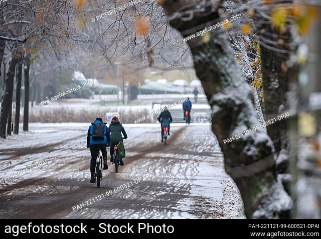 21 November 2022, Saxony, Leipzig: Cyclists ride along the snow-covered Brucknerallee in Leipzig's Clara Zetkin Park. After winter's flying visit