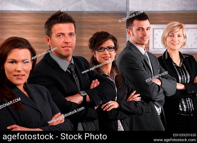 Portrait of business team standing in a row with arms crossed, smiling