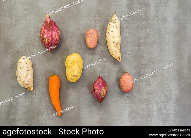 Great concept of healthy food, various vegetables, potatoes, sweet potatoes, carrots, on gray background, polished concrete