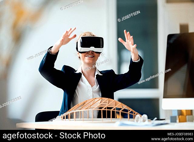 Businesswoman wearing virtual reality headset gesturing at office