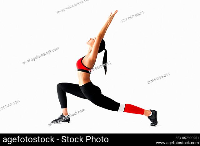 Young sporty woman doing yoga asana Warrior I Pose and stretching on white background. Practicing yoga, wellbeing and healthy lifestyle