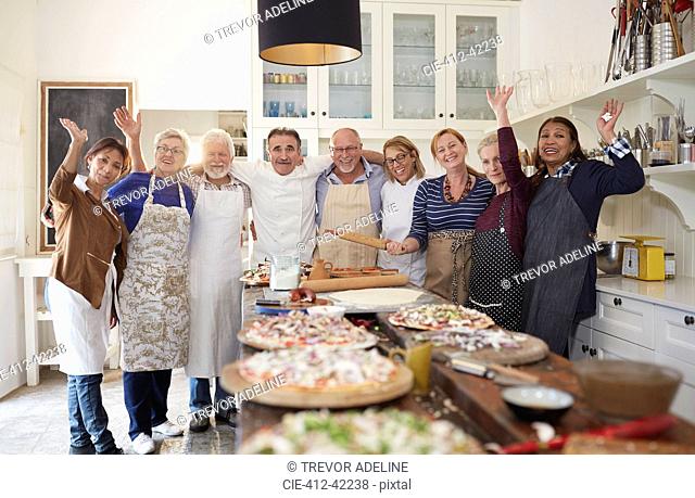 Portrait confident active senior friends and chef taking pizza cooking class