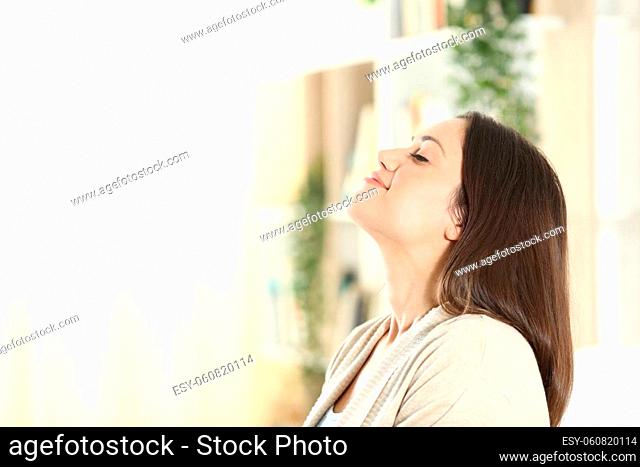 Side view portrait of a relaxed woman breathing fresh air at cozy home