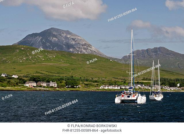 View of yachts moored in bay, with Beinn Shiantaidh and Corra Bheinn, Paps of Jura in background, Craighouse Bay, Isle of Jura, Inner Hebrides, Scotland