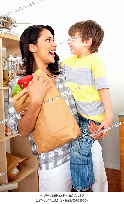 Cute Little boy unpacking grocery bag with his mother