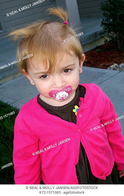 Shy young girl with a pacifier