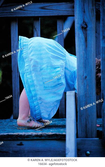 Little girl in blue denim dress bending over