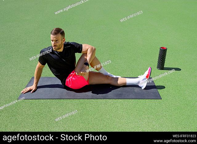 Sportsman doing stretching on exercise mat