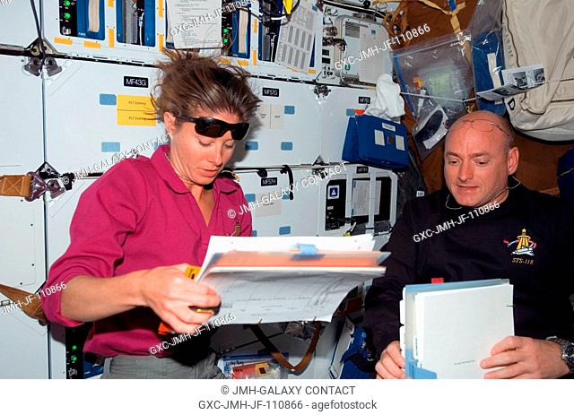 Astronauts Scott Kelly (right), STS-118 commander, and Tracy Caldwell, mission specialist, look over procedures checklists on the middeck of Space Shuttle...