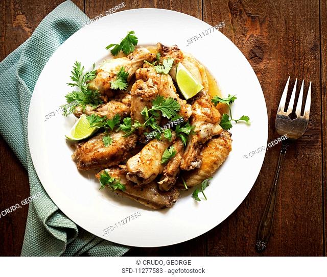 Jerk chicken wings with lime wedges and coriander