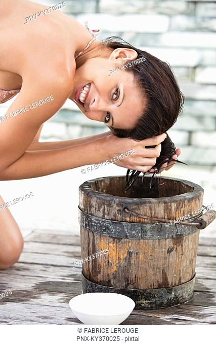 Portrait of a woman washing hair into a bucket