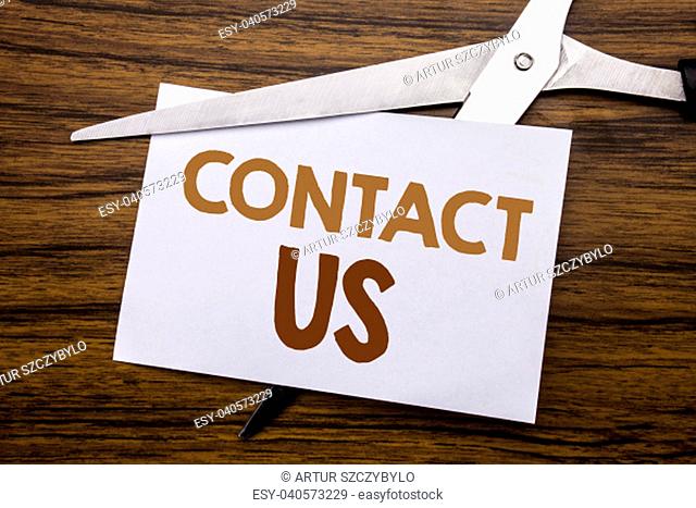 Hand writing text caption inspiration showing Contact Us. Business concept for Customer Support Written on note, wooden with colourful scissors meaning destroy...
