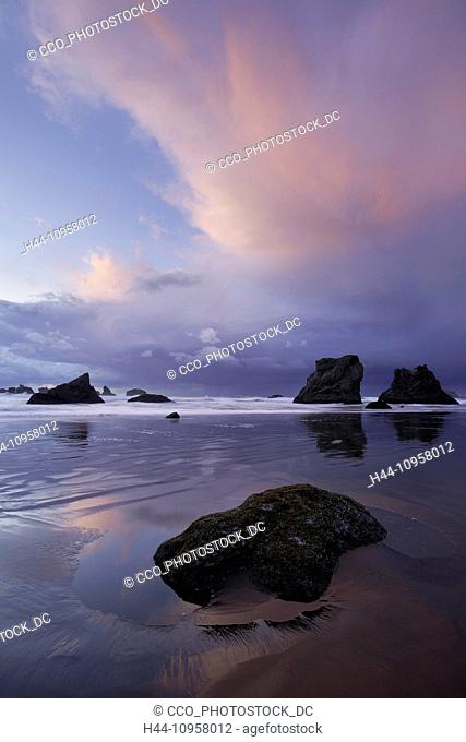 A storm brews over tidepools and sea stacks, rocks, at sunset along Bandon Beach, Oregon. Winter. USA