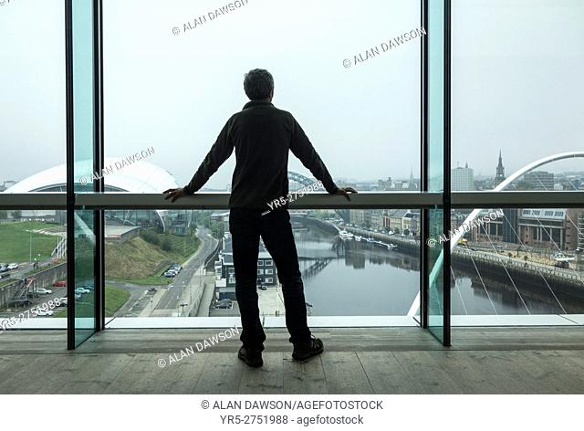 Gateshead, north east England, United Kingdom. A man looks out over the river Tyne towards Newcastle city centre from the viewing platform in The Baltic Centre...
