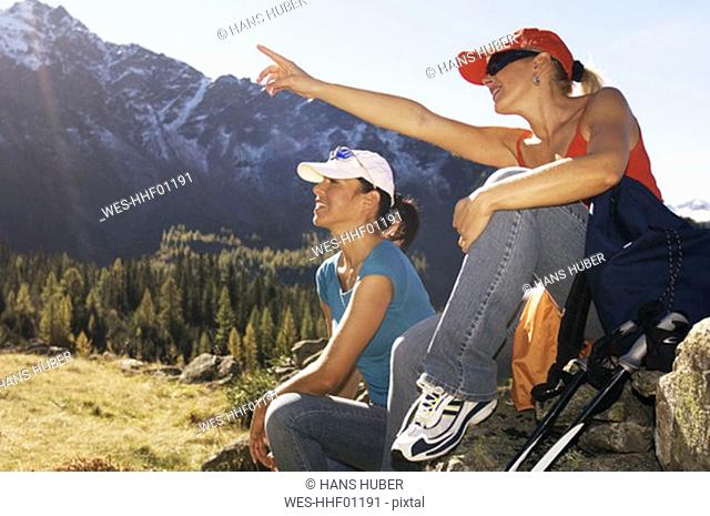 Two women in mountains, sitting on rock