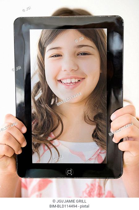 Hispanic girl holding tablet with picture of her face