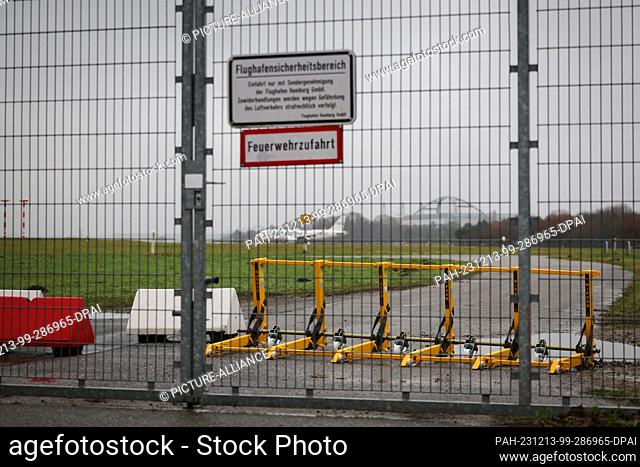 PRODUCTION - 13 December 2023, Hamburg: A mobile ram protection system secures an entrance to the airfield at the southern end of Hamburg Airport while an...