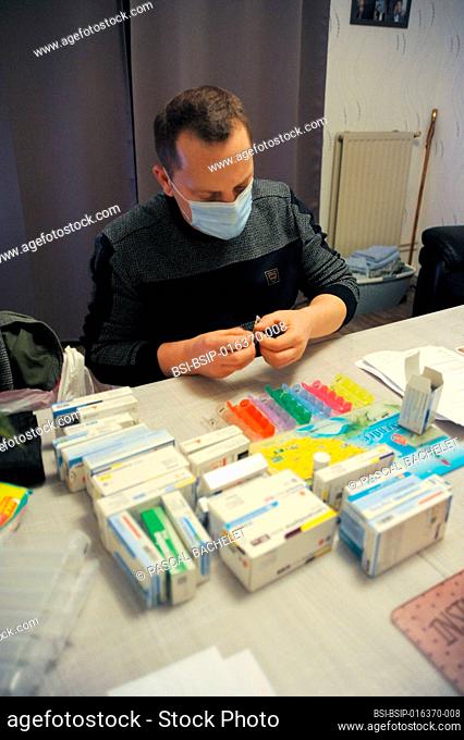 A private nurse prepares a pill box at a patient's home