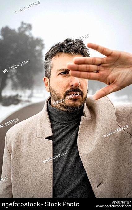 Mature man covering eye with hand during winter