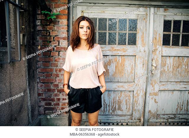 Young attractive brunette woman stands in front of garage door
