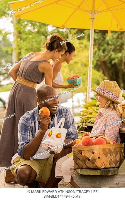 Vendor showing produce to girl at farmers market