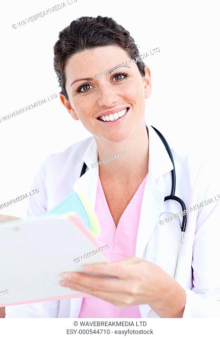 Brunette nurse reading paper and holding a stethoscope against a white background