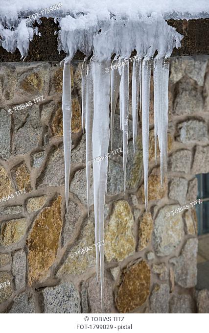 Icicles hanging over stone house roof