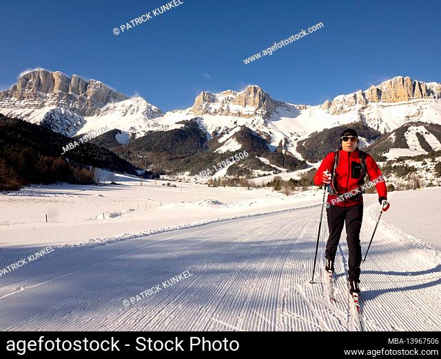 Cross-country skiers on the cross-country trail in Gresse-en-Vercors. In the background the Grand Veymont. Auvergne Rhone-Alpes