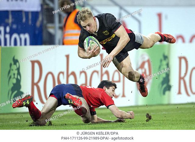 Chile's Tomas Ianiszewski (15), who lies on the ground, brings Germany's Tim Lichtenberg (14) down during the rugby international match between Germany and...