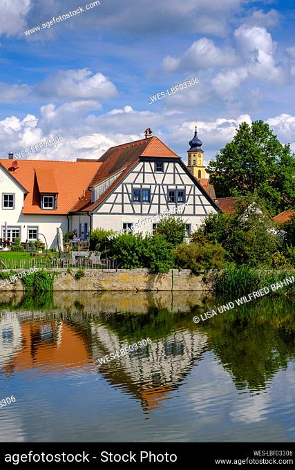Germany, Bavaria, Wassertrudingen, Wornitzpark watermill reflecting in Wornitz River