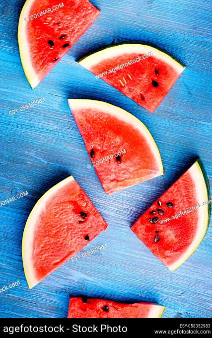 Slices of ripe watermelon on a blue wooden countertop