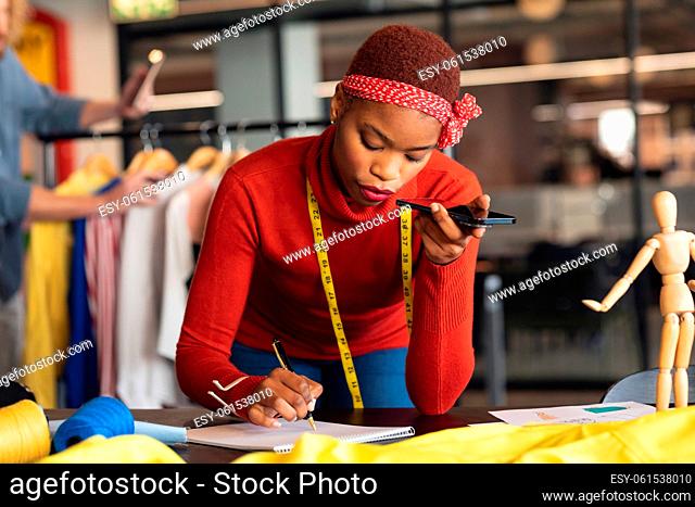 African american young female fashion designer taking order through mobile phone in studio office