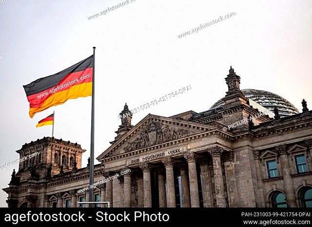 03 October 2023, Berlin: The German flag flies in front of the Reichstag building on the anniversary of the reunification of the two German states on October 3