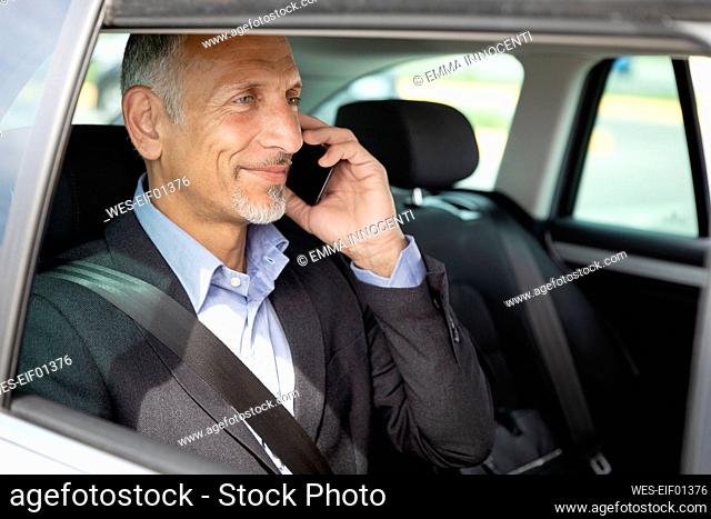 Smiling male professional talking on mobile phone in car