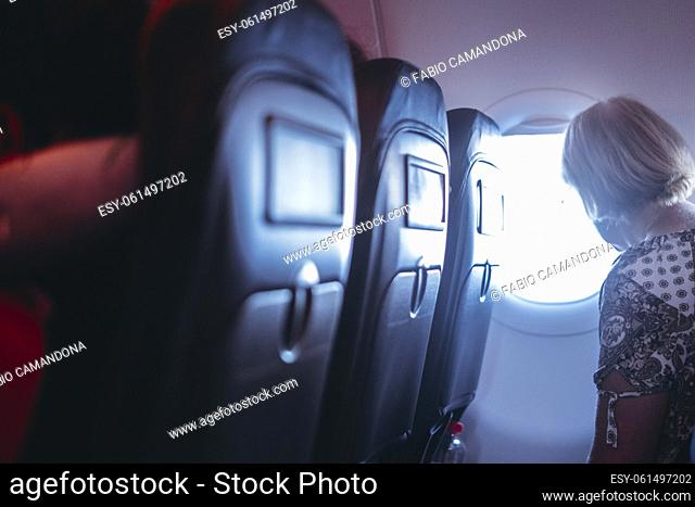 Side view of flight passenger enjoying travel and looking outside the window. People sit in aircraft seats. Vacation holiday trip concept