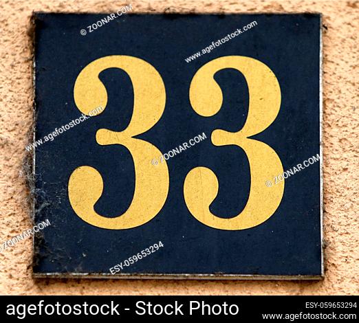 Vintage grunge square metal rusty plate of number of street address with number. Close up, brand. 33