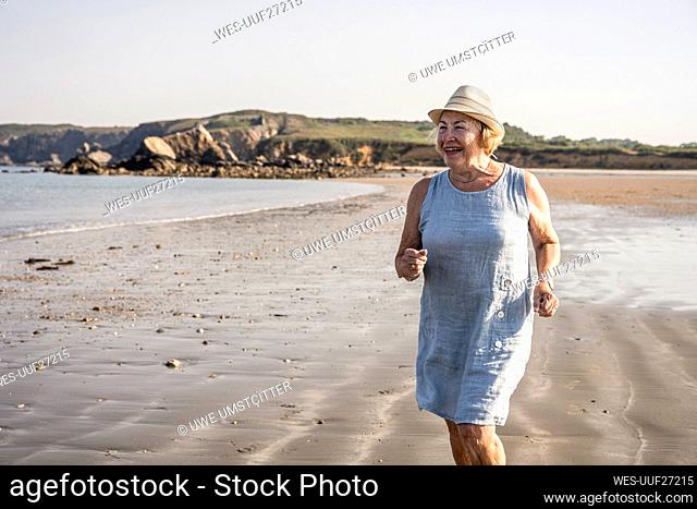 Happy senior woman wearing hat having fun at beach