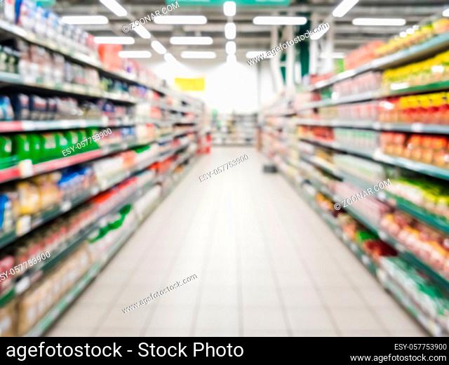 Blurred supermarket aisle with colorful shelves of merchandise. Perspective view of abstract supermarket aisle with copy space in center