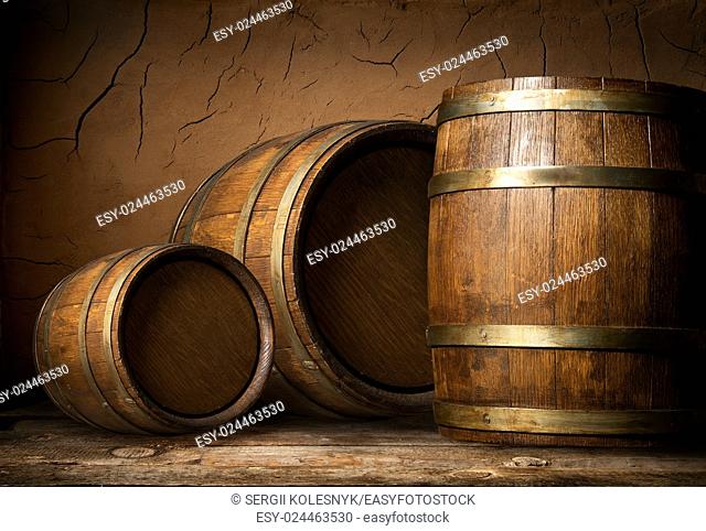 Three wooden barrels near clay wall in cellar