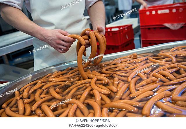 A butcher holds fresh sausages in his hands at the booth of the German butchers' association at the Internationale Handwerksmesse (IHM, lit