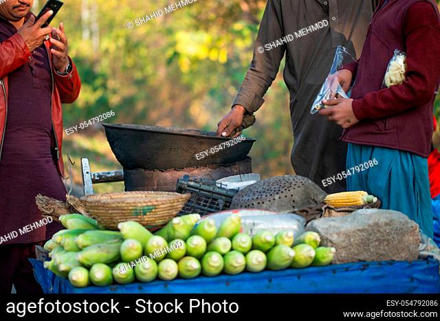 Islamabad, Islamabad Capital Territory, Pakistan - February 2, 2020, A Young boy is roasting fresh corn for the customers