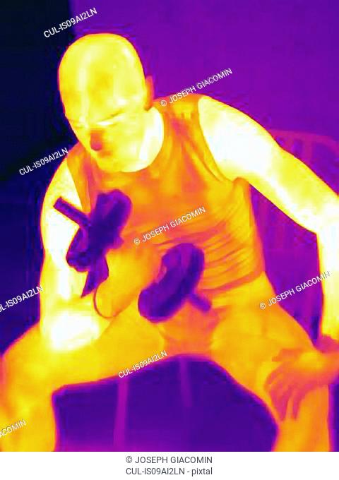 Thermal image of young male training with barbell. The image shows the heat produced by the muscles