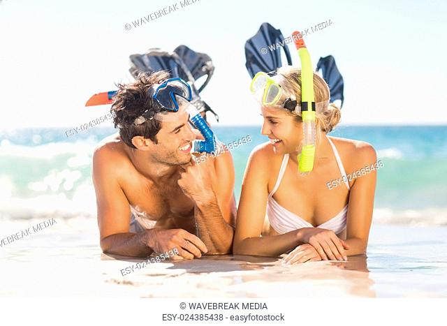 Young couple wearing diving mask lying on beach