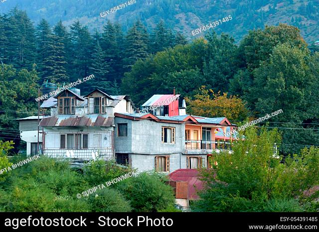 Panoramic Old Hotel cottage retro style building surrounded with pine woodland trees in springtime himalayan mountain valley