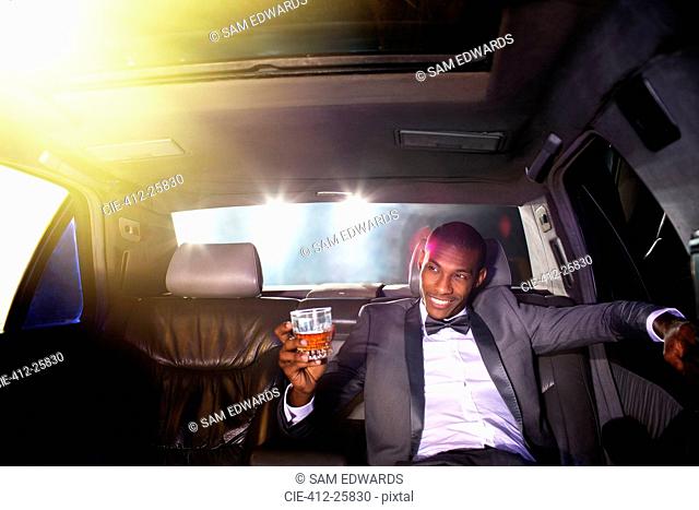 Celebrity drinking cocktail inside limousine outside event