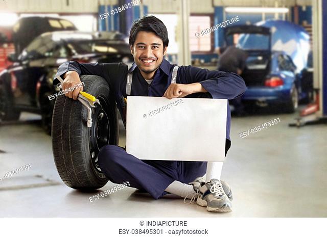 Car mechanic holding blank card in garage