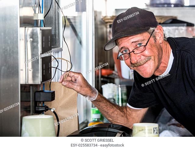 Smiling worker with order from inside food truck